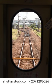 A view of train tracks from an oval train window