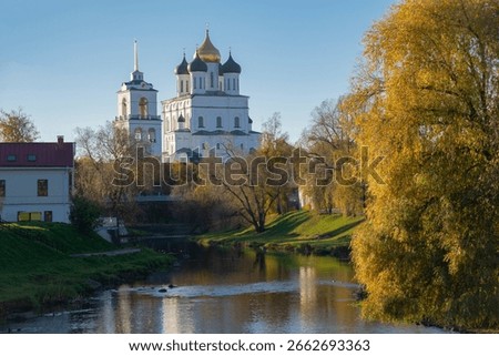 View of the Trinity Cathedral and Bell tower from the Pskova River in golden autumn. Pskov, Russia