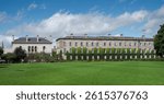 View of Trinity College, Dublin, Ireland, with a large open grass field, neatly trimmed hedges, and trees in front of a classical architecture building
