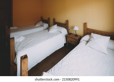 View Of A Triple Room With Three Wooden Beds In A Spanish Village Hotel.