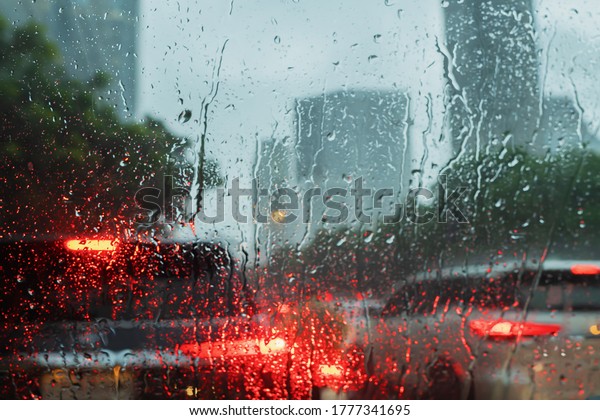 View of tropical rain from a car\
window. Street lights out of focus. Blurred\
background.