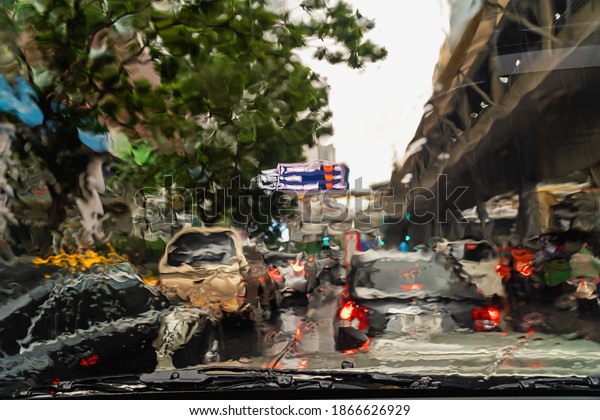 View of tropical rain from a car\
window. Street lights out of focus. Blurred\
background.