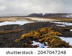 View of the tundra and hills. In the distance, there is a working village of miners near a gold ore deposit. August, cold snowy summer in the Arctic. Mayskoye mine, Chukotka, Siberia, Far North Russia