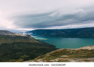 View Of The Turquoise Lake, Framed By Low Mountains In The Tundra. Storm Clouds. Kola Peninsula. Seydozero. Russia.