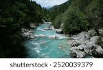 View of the turquoise, rushing waters of the Soca River in the Julian Alps of Slovenia. Beautiful mountain river flowing through evergreen forest.