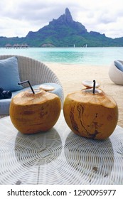 View of two fresh drinking coconuts on a table in front of the Mont Otemanu mountain in Bora Bora, French Polynesia, South Pacific