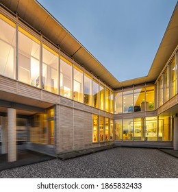 View of the two legs of a sustainable wood office building from the inner courtyard with lighting at night