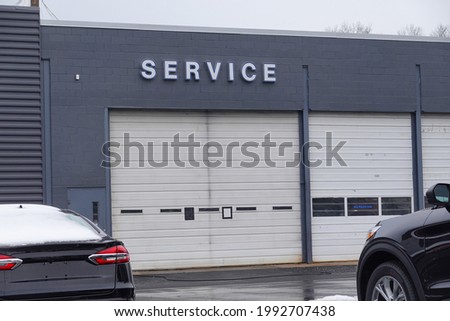 View of two overhead garage doors with the word service on the gray wall above one of the doors