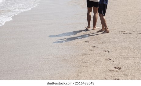 View of two pairs of children's feet playing on the beach leaving footprints - Powered by Shutterstock