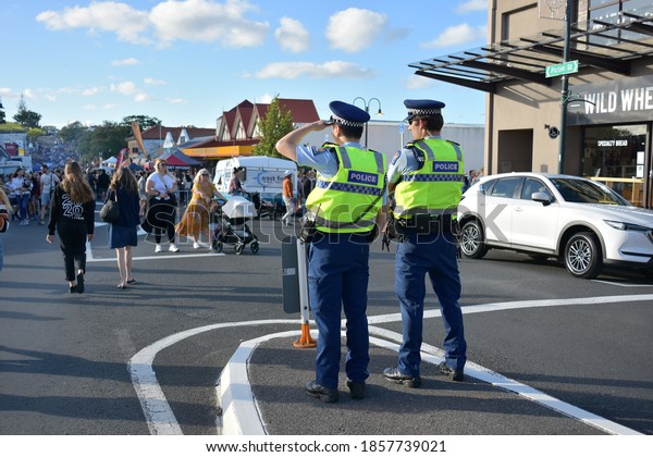 View of two policemen observing crowd
filling in Picton Street during Christmas community market in
Howick. Auckland, New Zealand - November 20
2020