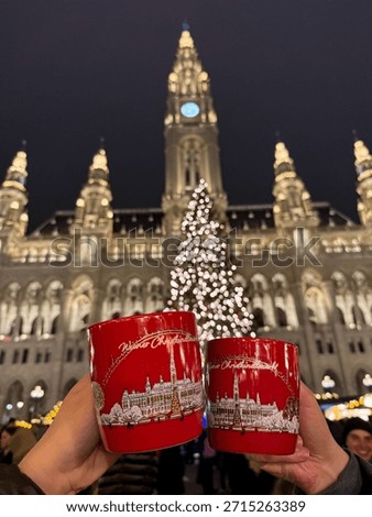 View of two red festive cups with mulled wine in couples hands on the famous Christkindlmarkt Christmas market on the Rathaus square at night
