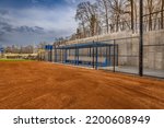 View of typical nondescript high school softball clay infield from infield near home plate looking toward the first base dugout.  No people visible.  Not a ticketed event.		