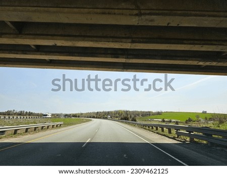 The view from under an overpass that stretches across a highway.