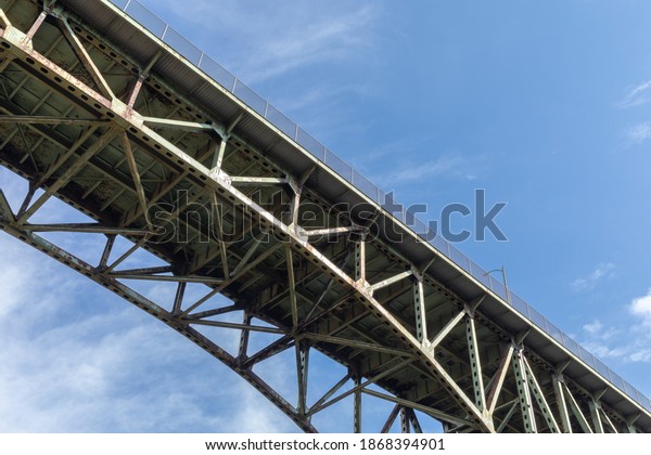 View\
from underneath an old arch highway bridge silhouetted against a\
blue sky, creative copy space, horizontal\
aspect