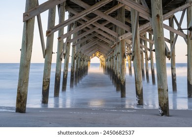 The view underneath a old rustic wooden fishing pier at sunset. Long exposure photo. - Powered by Shutterstock