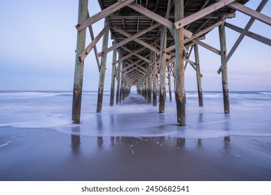 The view underneath a old rustic wooden fishing pier at sunset. Long exposure photo. - Powered by Shutterstock