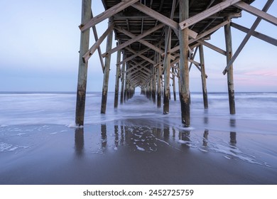 The view underneath an old rustic wooden fishing pier at sunset. Long exposure photo. - Powered by Shutterstock