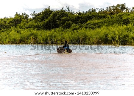 View of an unidentified man rowing in his boat. Tonle Sap refers to a freshwater lake that form the central part of cambodian hydrological system