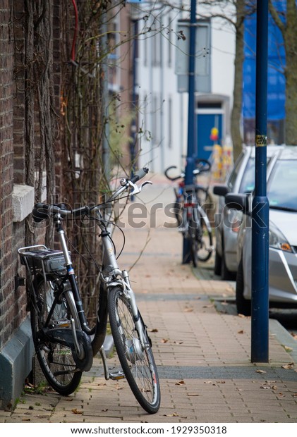 A\
view of an urban sidewalk with parked bicycles and\
cars