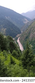 A view of valley with clouds, trees and a stream