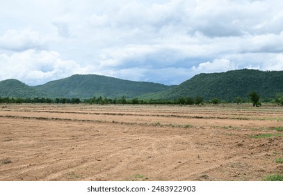 View of Vast empty land with trees and mountains with natural blue sky background at Thailand.