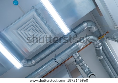 View of the ventilation pipes under ceiling. Ventilation pipes bottom view. Chrome plated pipes from an industrial hood. Concept is an industrial ventilation system. Air purification system