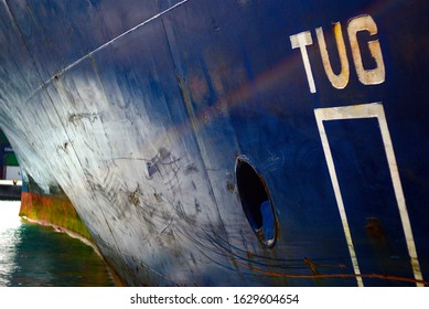 View of very large container ship port bow part with point for tug pushing. Metal is damaged and rusty.