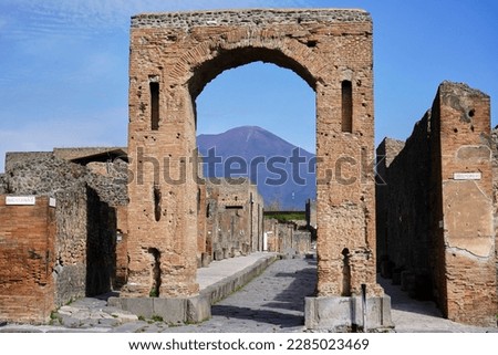 View of Vesuvius volcano through a wall arch in the ancient Roman ruined city of Pompeii.