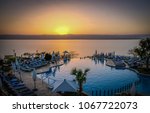 View of the vibrant sunset from a hotel resort infinity pool overlooking the Dead Sean on a warm evening in Jordan