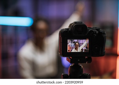 View Of Video Camera Screen With Attractive Confident African American Skilled Business Woman Explaining Online Economic Charts On Glass Board To Her Colleagues.