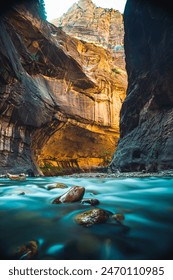 A view of the Virgin River flowing through a narrow canyon in Zion National Park. The water is turquoise blue and the canyon walls are brown and gray.