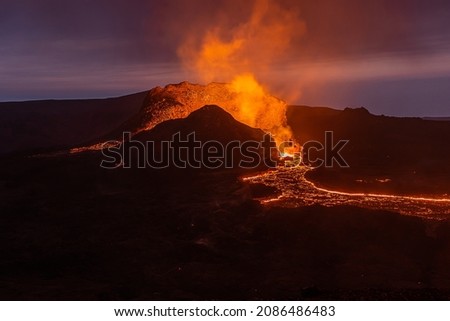 View of volcanic eruption in Iceland. Crater from the volcano Fagradalsfjall at night to the blue sky with liquid lava. Volcano on the Reykjanes peninsula in the GeoPark.