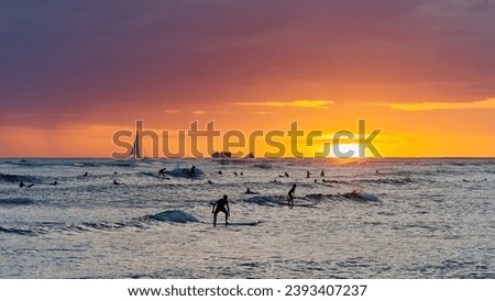 View from Waikiki beach at beautiful sunset with silhouettes of swimmers and surfers, Honolulu, Oahu, Hawaii, USA