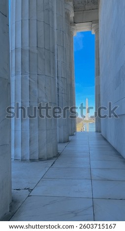 View of the Washington Monument and U.S. Capitol framed by the marble columns of the Lincoln Memorial on a clear day in Washington, D.C.