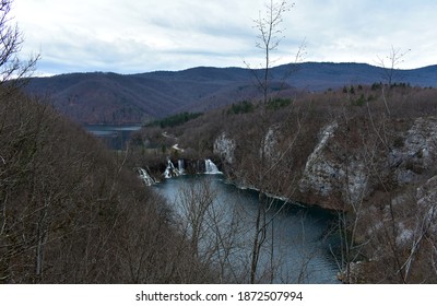 View Of The Waterfalls And Dark Hills From A Vantage Point. We Can See A Winding Dirt Road In The Middle Of The Image.