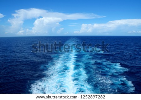 The view of waves and blue ocean from behind a cruiseship