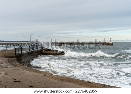 View of waves crashing at the harbour wall in Amble, Northumberland, UK