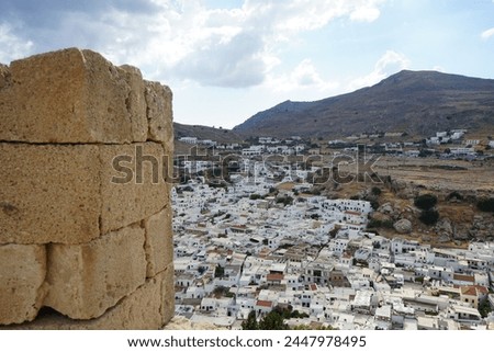 View of the white houses of the 16th-18th centuries from the ancient Acropolis of Lindos in August. Lindos is an archaeological site, a fishing village. Rhodes, Dodecanese, Greece