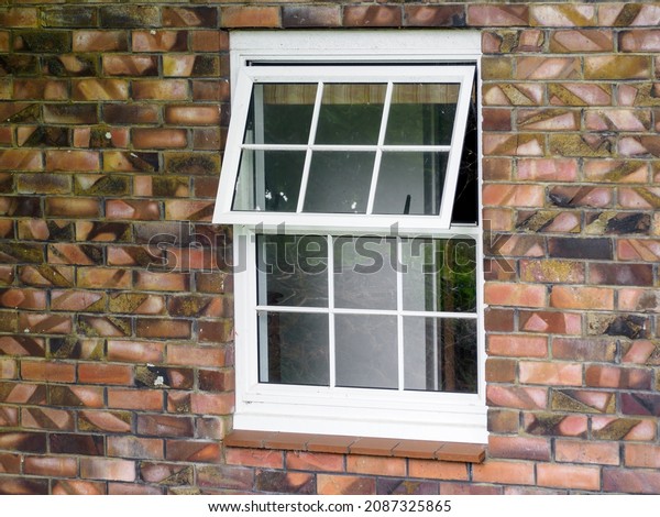 View\
of white wooden divided awning window on brick\
wall