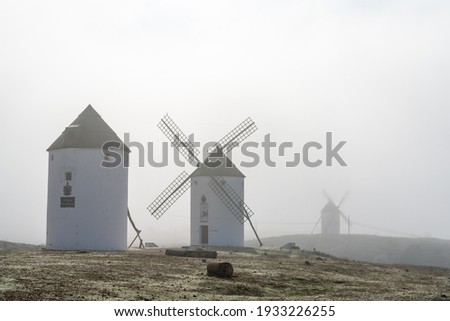 View of whitewashed windmills in La Mancha on a foggy morning