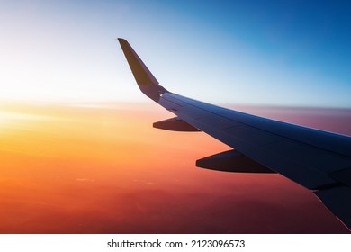 View from the window of the aircraft on the wing over the colorful sunset and illuminated vivid clouds - Powered by Shutterstock