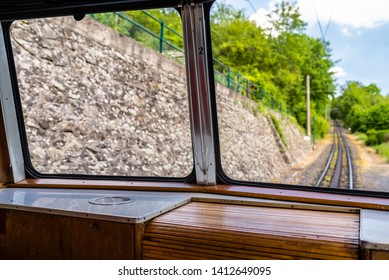 A view from the window of a moving train, visible tracks, trees and blue sky with white clouds.
