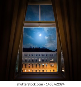 The View From The Window Of The Old Night City Of Vienna And The Moon In The Cloudy Sky.