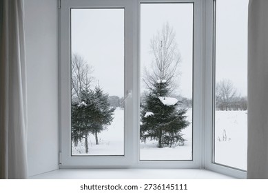 View from the window on trees under the snow, snow-covered park, garden,  landscape with a winter forest.