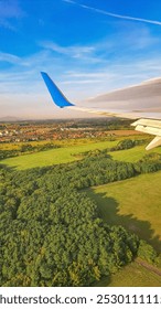 view from the window of the plane - a wing and underneath multi-colored fields, meadows, forests and houses