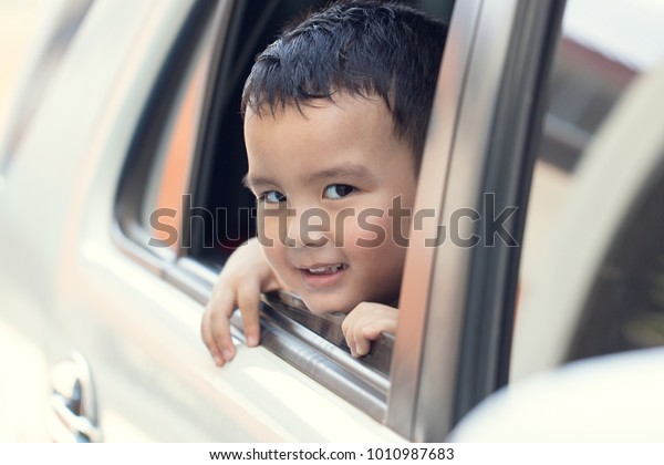 View from\
window, Portrait cute boy sitting in the car and look straight\
ahead at camera. He has tan skin and is messing around. Do not\
forget the kids. Soft focus and copy\
space.