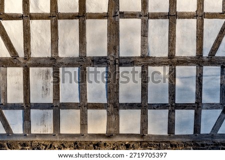 View of a windowless exterior or interior wall of a medieval half-timbered building with compartments and slightly weathered wooden beams.