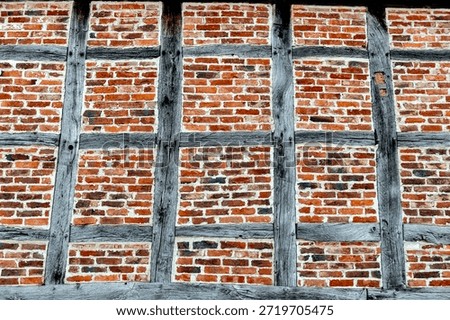 View of a windowless exterior or interior wall of a medieval half-timbered building with compartments and slightly weathered wooden beams.
