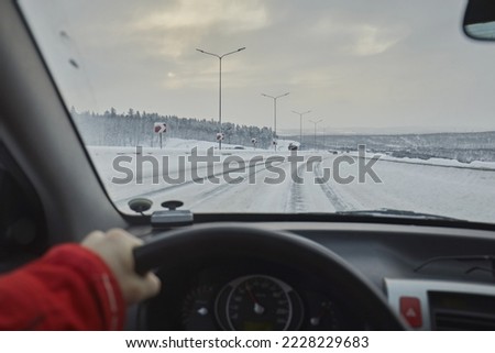View from the windshield of a car on a snowy road with snow ruts. driver's hands and dangerous driving in winter Imagine de stoc © 