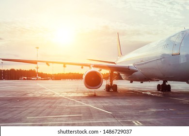 View of the wing and engine of a long-range passenger aircraft, evening airport at sunset